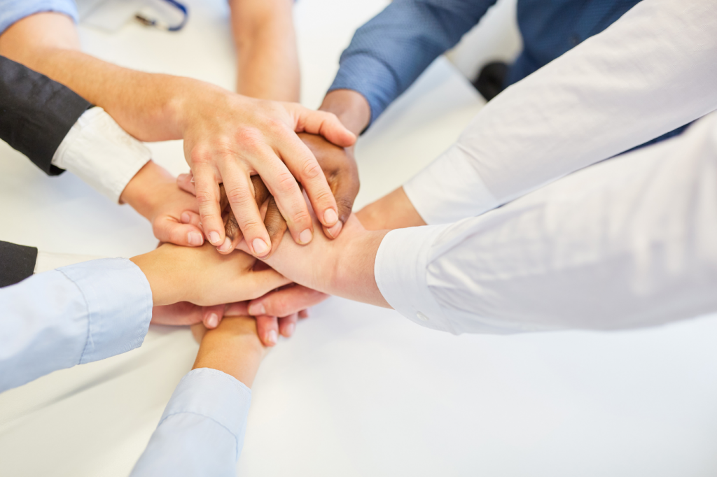 Different people's hands reaching in to demonstrate how using a software for fund accounting for charities is a team sport.